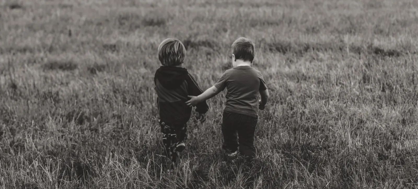 Zwei Kinder gehen gemeinsam über eine Wiese